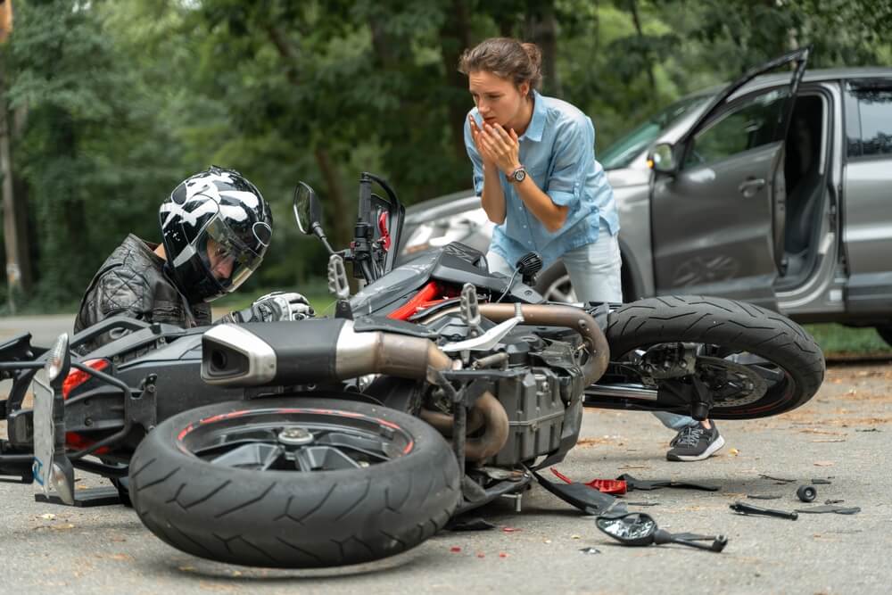 Motorcycle accident scene with injured rider and concerned driver, used for Nampa motorcycle accident lawyer information.